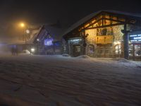 a man walks out to the lodge in a snowy night with snow piled on the ground