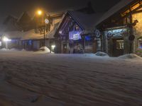 a man walks out to the lodge in a snowy night with snow piled on the ground