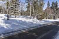 this is a snowy road that looks very empty while you can see it in the sun