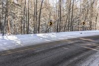 an empty road is surrounded by trees and snow on both sides of the road and in the middle there are a lot of trees