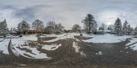 a panorama of a road and two fire hydrants covered in snow near some trees