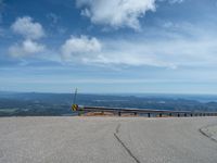 an empty road and a hill overlook the view of mountains and clouds and blue sky