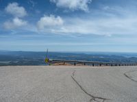 an empty road and a hill overlook the view of mountains and clouds and blue sky