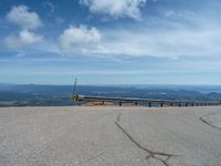 an empty road and a hill overlook the view of mountains and clouds and blue sky