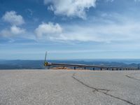 an empty road and a hill overlook the view of mountains and clouds and blue sky