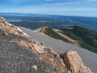 a snow covered road is near a very steep cliff on a clear day the wall is filled with snow and snow