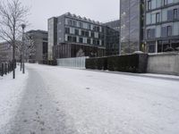 a person walks down the road in the snow on a snowy day, with apartment buildings