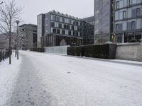 a person walks down the road in the snow on a snowy day, with apartment buildings