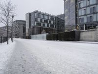 a person walks down the road in the snow on a snowy day, with apartment buildings