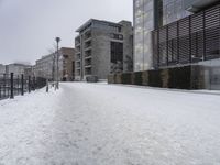 a person walks down the road in the snow on a snowy day, with apartment buildings