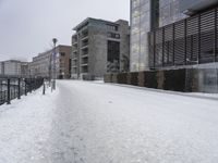 a person walks down the road in the snow on a snowy day, with apartment buildings