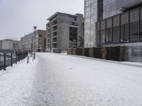 a person walks down the road in the snow on a snowy day, with apartment buildings