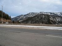 the roadway is wide and paved with many stone blocks in front of it there are several trees, a mountain and road in the background