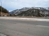 the roadway is wide and paved with many stone blocks in front of it there are several trees, a mountain and road in the background