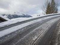 a snow covered road with some skis and trees on the side of it and snow capped hills in the background