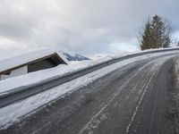 a snow covered road with some skis and trees on the side of it and snow capped hills in the background
