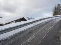 a snow covered road with some skis and trees on the side of it and snow capped hills in the background