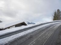 a snow covered road with some skis and trees on the side of it and snow capped hills in the background