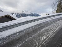 a snow covered road with some skis and trees on the side of it and snow capped hills in the background