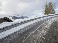 a snow covered road with some skis and trees on the side of it and snow capped hills in the background