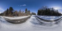 a view through a fish eye lens looking into snow on a road in the woods