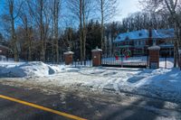 a red fire hydrant is next to snow and fenced in parking lot that is empty