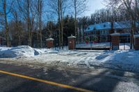 a red fire hydrant is next to snow and fenced in parking lot that is empty