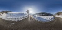 two roads covered in snow on the ground in front of a mountain range with trees