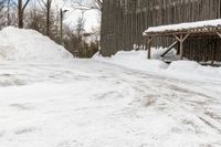 there is a wooden shelter in the middle of a snowy area with dirt piled up on the ground