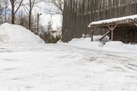 there is a wooden shelter in the middle of a snowy area with dirt piled up on the ground