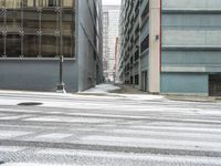 a street corner is snowy covered in snow and empty parking spaces in the background is a tall building with windows