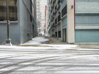 a street corner is snowy covered in snow and empty parking spaces in the background is a tall building with windows