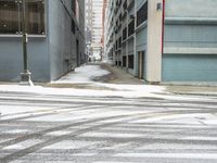 a street corner is snowy covered in snow and empty parking spaces in the background is a tall building with windows