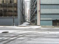 a street corner is snowy covered in snow and empty parking spaces in the background is a tall building with windows