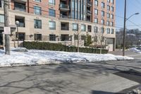 a street corner with white snow on the ground and a big building on the opposite side