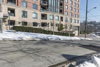 a street corner with white snow on the ground and a big building on the opposite side