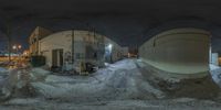 an image of a street at night taken from an 360 - angle lens of snow