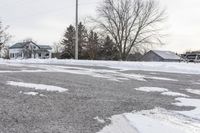 there are snow on the ground of this street near a house with two trees in the background