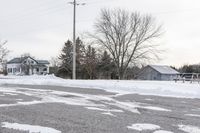 there are snow on the ground of this street near a house with two trees in the background