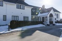 the white home is located on a snow - filled suburban street with a fence that has a few snow piles