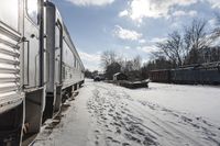 the front view of an outdoor train traveling down the tracks in the winter, with snow all around and train tracks on the ground