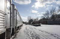 the front view of an outdoor train traveling down the tracks in the winter, with snow all around and train tracks on the ground