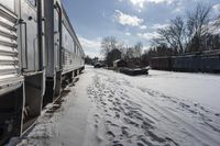 the front view of an outdoor train traveling down the tracks in the winter, with snow all around and train tracks on the ground