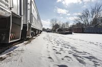 the front view of an outdoor train traveling down the tracks in the winter, with snow all around and train tracks on the ground