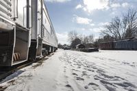 the front view of an outdoor train traveling down the tracks in the winter, with snow all around and train tracks on the ground