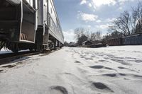 the front view of an outdoor train traveling down the tracks in the winter, with snow all around and train tracks on the ground