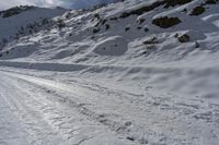 a person riding skis on a snowy trail with rocky cliffs in the background wearing a hat and gloves