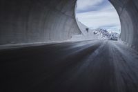 a tunnel with snow and mountains in the background with blurry photograph from inside of it