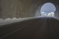 a tunnel with snow and mountains in the background with blurry photograph from inside of it