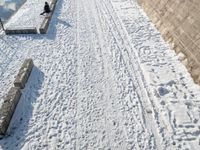 a person standing in the snow on the edge of a walkway at a lake bank